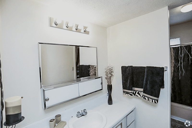 a bathroom with a sink and a mirror at Gatehouse Apartments, Kansas City